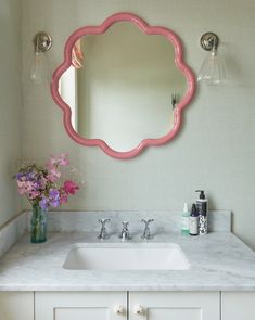 a bathroom sink with a pink mirror above it