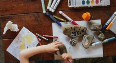 a young child is painting rocks with crayons and colored pencils on a piece of paper