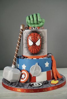 a spiderman themed birthday cake with green hands on top and other decorations around it