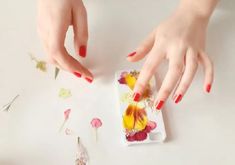 two hands with red and yellow nail polish on their fingertipss over a white plate