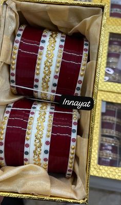 two red and white bracelets are in a box with gold chains on the sides