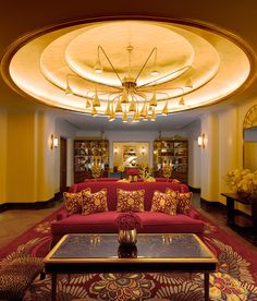 a living room filled with red couches and lots of furniture under a chandelier