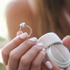 a woman holding an engagement ring in her hand