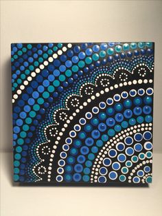 a blue and white painting with circles on it's side, sitting on a shelf