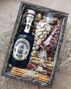 a bottle of beer sitting in a box filled with nuts and pretzel sticks