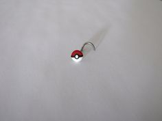 a red and black pokeball on a white surface with a metal hook in the middle