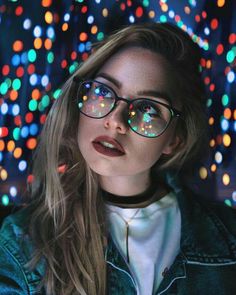 a woman wearing glasses with colorful lights in the background