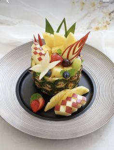 a pineapple topped with fruit on top of a black plate