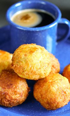 some fried food on a blue plate next to a cup of coffee