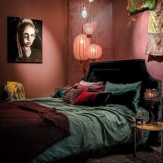 a bedroom with red walls and green bedspread on the bed is lit by two hanging lights