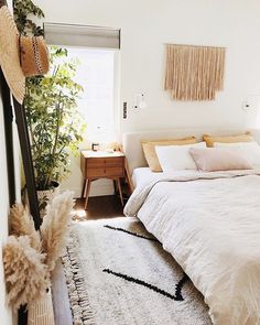 a bedroom with a bed, rug and plants