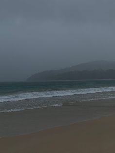 two people walking on the beach with an umbrella