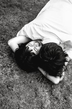 black and white photograph of a woman laying on the ground with her head in her hands