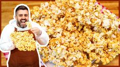 a man in an apron holding up a spoon with popcorn on it next to a pile of corn