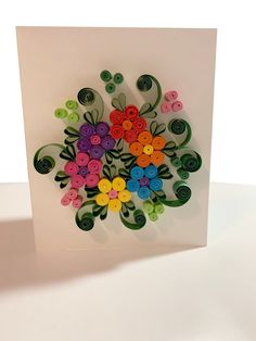 a white card with colorful buttons and flowers on the front, sitting on a table