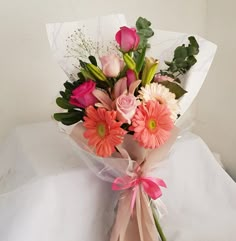 a bouquet of flowers sitting on top of a white sheet with pink and orange flowers