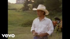 a man wearing a cowboy hat standing in the grass