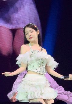 a woman in a white dress on stage with her hands out to the side,