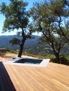 an outdoor hot tub sitting on top of a wooden deck next to two large trees