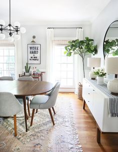 the dining room table is surrounded by gray chairs and an area rug with plants on it