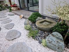 a garden with rocks and plants in front of a glass door that leads to an outside patio