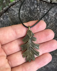 a hand holding a bronze pendant with an oak leaf on it