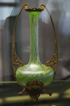 a green glass vase sitting on top of a table