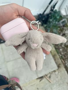 a person holding a stuffed animal keychain in their right hand and a pink cup on the left