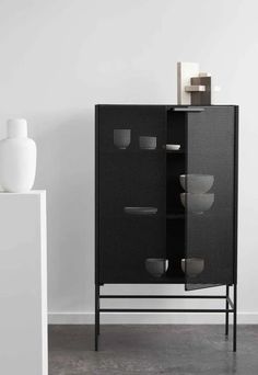 a black cabinet sitting next to a white vase