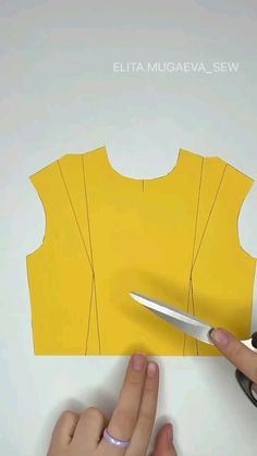 someone cutting out a yellow top with scissors