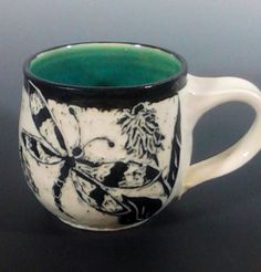 a black and white coffee cup with green inside sitting on top of a dark table