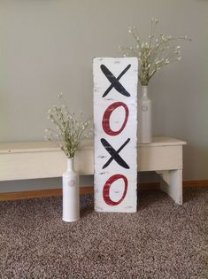 two vases with flowers are sitting next to a sign that says xoxo