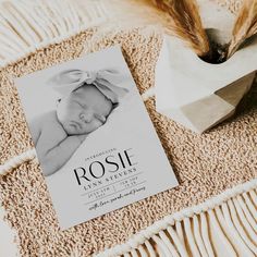 a baby's birth announcement is laying on the floor next to a vase with feathers