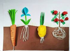 some paper flowers and carrots are on a brown piece of paper with roots attached to them