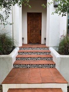 a set of steps leading up to a front door with decorative tiles on the outside