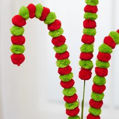 two red and green pom - poms are arranged in the shape of a candy cane