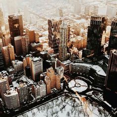 an aerial view of a city with tall buildings and snow covered ground in the foreground