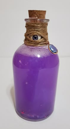 a purple glass bottle with an evil eye on it's lid and rope wrapped around the top