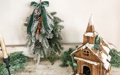 a christmas tree with pine cones and evergreens next to a small church ornament