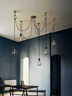 a dining room with blue walls and wooden flooring, chandeliers hanging from the ceiling