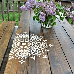 a wooden table topped with a vase filled with purple flowers