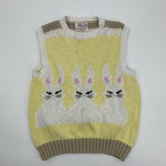 a yellow sweater with rabbits on it and two white ones in the middle, sitting next to each other