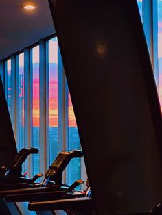 there are many treadmills lined up in the room with blinds on the windows