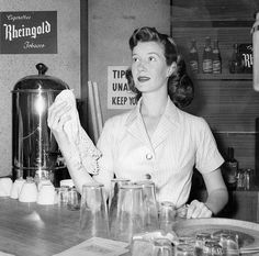 a woman standing in front of a counter filled with glasses