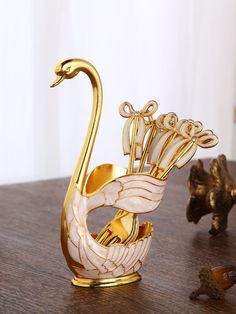 a golden swan figurine sitting on top of a wooden table next to other items