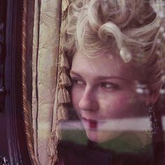 a woman with blonde hair looking out the window