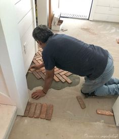 a man is laying bricks on the floor