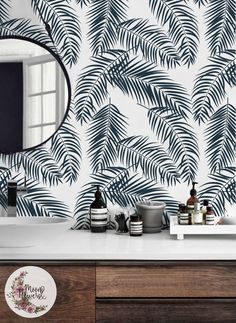 a bathroom vanity with a mirror and palm leaf wallpaper on the wall behind it