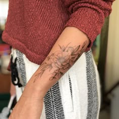 a woman's arm with a flower tattoo on the left side of her arm