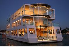 a large white boat floating on top of a body of water next to a tall building